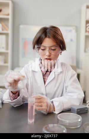 Ritratto Vertican di ragazza carina godendo di esperimenti scientifici in classe chimica e indossare indumenti protettivi Foto Stock