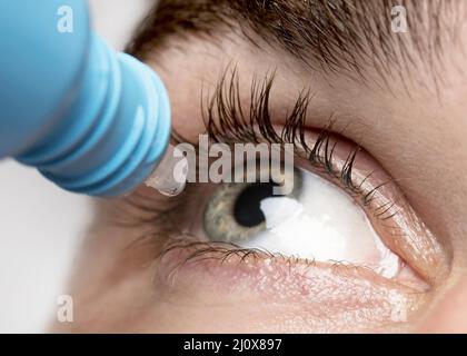 Uomo che usa collirio close up Foto Stock