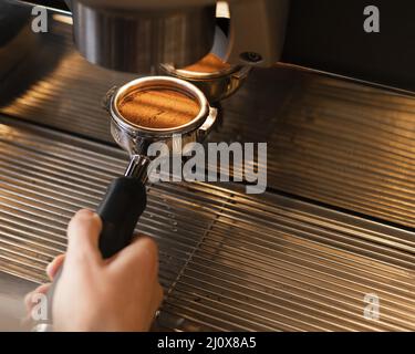 Chiudere la mano per preparare il caffè con la macchina. Concetto di foto di alta qualità Foto Stock