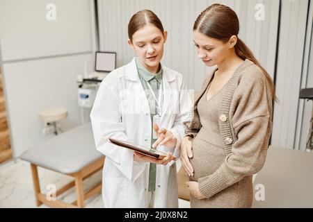 Vita ritratto di giovane medico donna consulenza donna in clinica e utilizzando tablet digitale Foto Stock