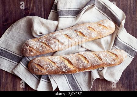 Baguette alla francese con crostini freschi fatti in casa. Due pagnotte su biancheria da letto Foto Stock