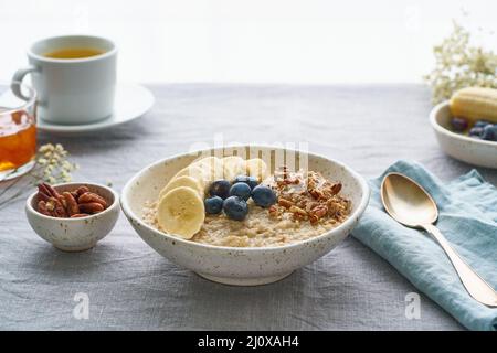 Farina d'avena intera, ciotola grande di porridge con banana, mirtilli, noci per la colazione, Foto Stock