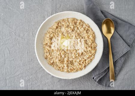 Farinata d'avena intera, ciotola grande di porridge con burro per colazione, pasto del mattino. Foto Stock