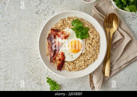 Farinata d'avena, uova fritte, pancetta fritta. Cibo equilibrato. Cibo intuitivo e consapevole, vista dall'alto, spazio per la copia Foto Stock