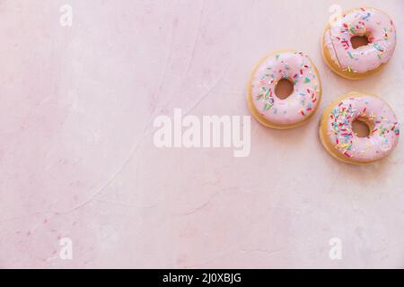 Vista dall'alto, ciambelle fresche con sfondo rosa cosparso. Concetto di foto di alta qualità Foto Stock