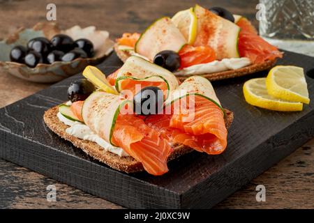 Smorrebrod - panini tradizionali danesi. Pane di segale nero con salmone, formaggio cremoso Foto Stock