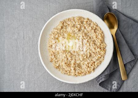 Farinata d'avena intera, ciotola grande di porridge con burro per colazione, pasto del mattino. Foto Stock