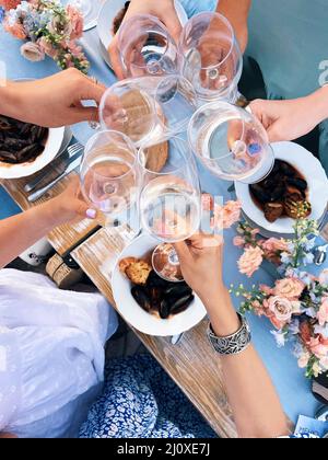 Gruppo di amici che allietano con bicchieri di vino bianco durante il picnic con cibo mediterraneo all'aperto Foto Stock