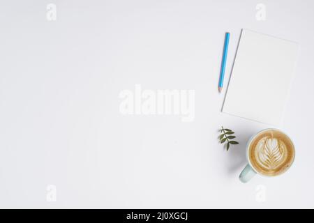 Carta bianca blu matita tazza cappuccino caffè sfondo bianco. Concetto di foto di alta qualità Foto Stock
