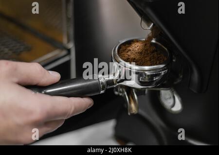 Chiudi il barista maschile utilizzando una macchina da caffè professionale Foto Stock