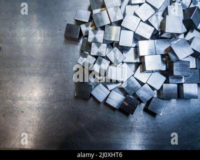 pila di piccoli cubi in acciaio lucido lavorato a macchina su superficie metallica Foto Stock