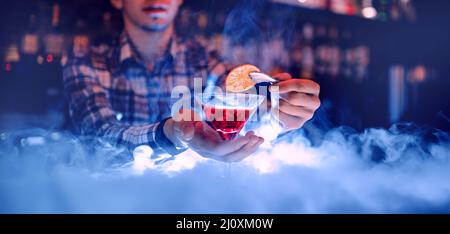 Cocktail rosso in calice martini con concetto di fumo e bevande barman. Foto Stock