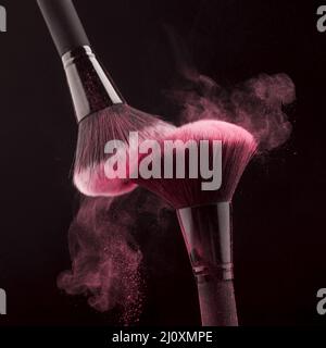 Pennelli per il trucco con polvere rosa vorticosa immagine sul pik. Concetto di foto di alta qualità Foto Stock