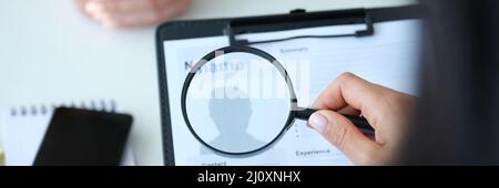 Datore di lavoro che guarda modulo di domanda con lente d'ingrandimento closeup Foto Stock