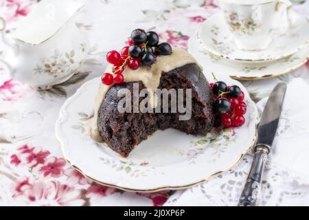 Budino tradizionale di prugna australiana con salsa di rum alla vaniglia e bacche fresche offerto come primo piano su un piatto di design Foto Stock