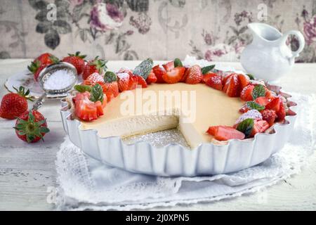 Cheesecake tradizionale tedesca con frutta a fragola servita come primo piano in una forma di supporto su un tavolo di legno Foto Stock