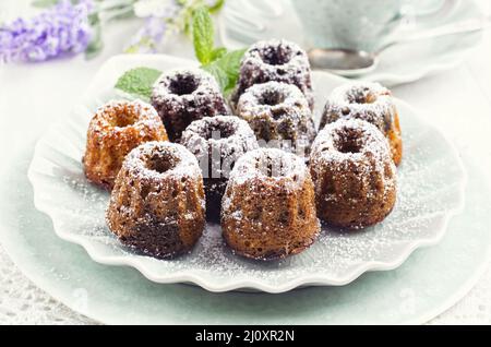 Tradizionale mini gugelhupf panca con zucchero a velo servito come primo piano su un piatto di design Foto Stock