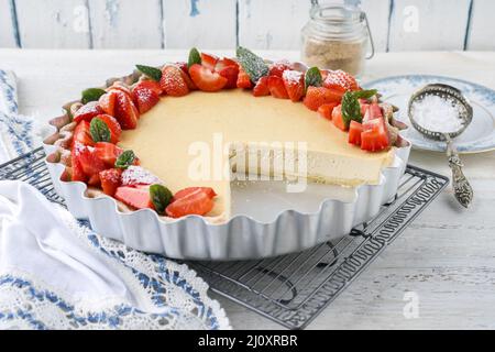 Cheesecake tradizionale tedesca con frutta a fragola servita come primo piano in una forma di supporto su un tavolo di legno Foto Stock