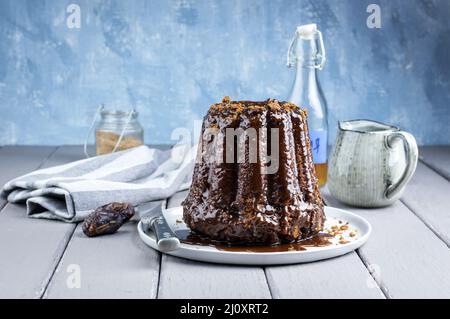 Tradizionale budino appiccicoso inglese con glassa al caramello servito da primo piano su un piatto di design Foto Stock