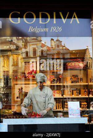 Un cioccolatiere al negozio di cioccolato Godaiva al Grand Place di Bruxelles, Belgio. Foto Stock