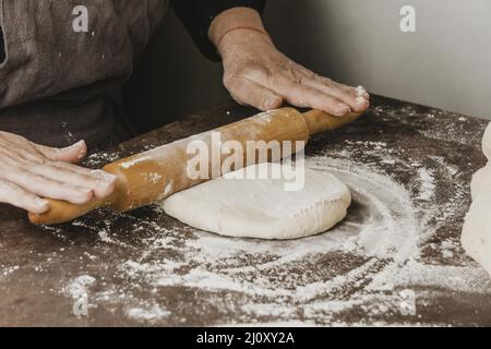 Chef femminile che utilizza pasta per pizza a spilla. Foto di alta qualità Foto Stock