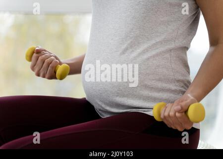 Donna incinta che usa pesi gialli. Foto di alta qualità Foto Stock