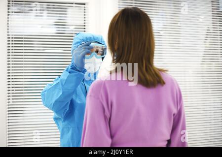 Infermiere in dispositivi di protezione individuale DPI che esegue il test PCR su pazienti in gravidanza, prendendo tampone nasale. Foto Stock