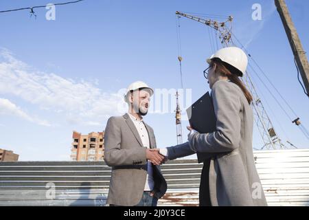 Gli ingegneri sorridenti scuotono le mani per il progetto architettonico del cantiere. Foto di alta qualità Foto Stock