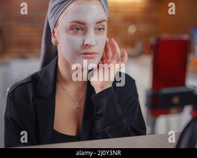 Famoso blogger. Allegro vlogger femmina che mostra maschera di bellezza durante la registrazione video e dando suggerimenti per il suo blog di bellezza. Donna test nuovo prodotto. Maschera cosmetica viso Foto Stock