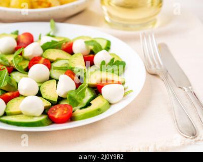 Insalata fresca con pomodori cetrioli rucola mozzarella e avocado. Olio con spezie Foto Stock