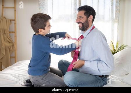 Figlio che aiutava suo padre a indossare la cravatta Foto Stock