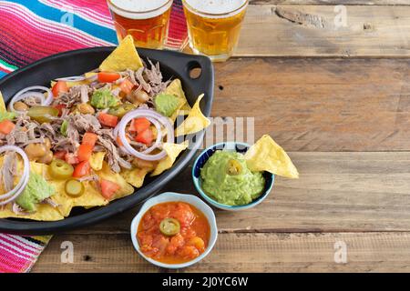 Vassoio in ceramica nera di nachos con ciotole di salsa di carne e birra con decorazioni messicane. Ciotole di salsa. Spazio di copia. Cucina messicana. Foto Stock