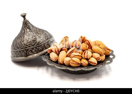 Pistacchi sgusciati isolati su sfondo bianco. Pistacchi su un piatto rustico da servitoPistacchi sgusciati isolati su sfondo bianco. Pistacchi o Foto Stock