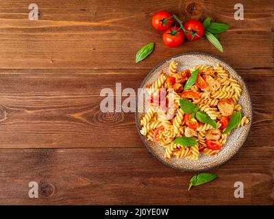 Fusilli con salsa di pomodoro, filetto di pollo con foglie di basilico Foto Stock