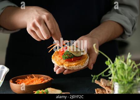 Donna che fa sandwich gustoso con hummus sano, primo piano Foto Stock