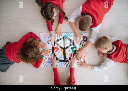 Vista dall'alto dei bambini che fanno un poster di segno di pace a scuola. Foto Stock