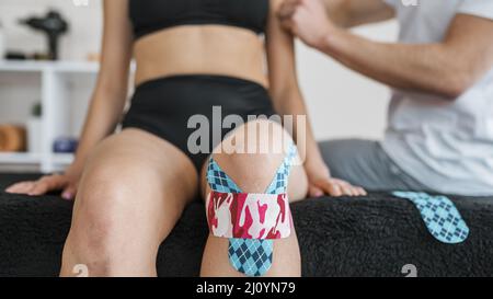 Fisioterapia femminile con nastro di rinforzo per ginocchio. Foto di alta qualità Foto Stock