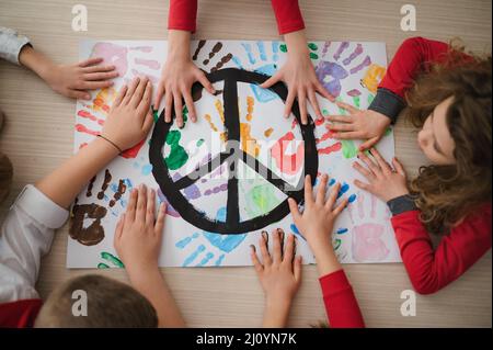 Vista dall'alto dei bambini che fanno un poster di segno di pace a scuola. Foto Stock