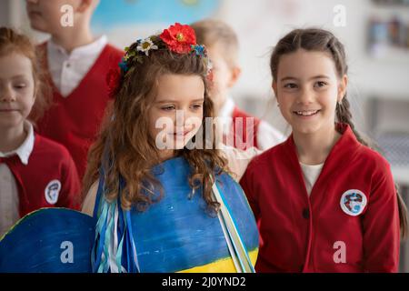 Scolari che accolgono il nuovo compagno di classe ucraino, concetto di iscrizione dei bambini ucraini alle scuole. Foto Stock