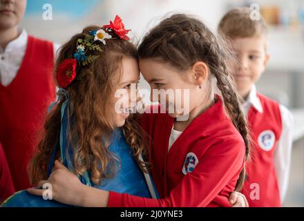 Scolari che accolgono il nuovo compagno di classe ucraino, concetto di iscrizione dei bambini ucraini alle scuole. Foto Stock