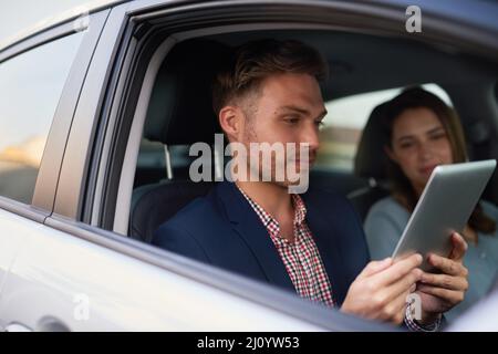 Trovare il percorso più intelligente da utilizzare. Scatto di un giovane che guarda un tablet mentre viaggia in auto con sua moglie. Foto Stock