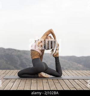 Donna con vista laterale che pratica yoga all'aperto Foto Stock