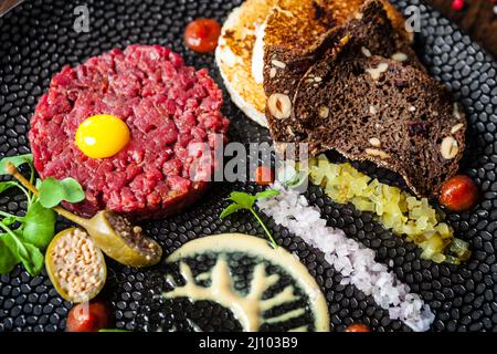 Tartare di manzo da Black Angus. Cipolla, uova di quaglia, salsa di pomodoro, maionese di senape. Delizioso e salutare primo piano di cucina italiana tradizionale servito per pranzo Foto Stock