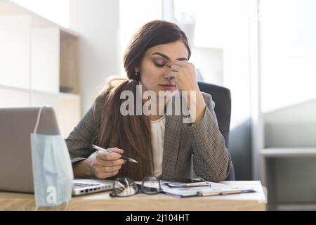 Donna d'affari stanca scrivania con computer portatile Foto Stock