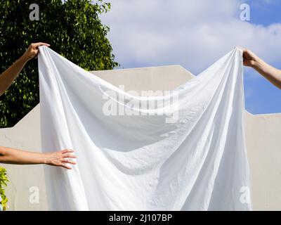 Chiudi due persone che appendono la linea bianca del foglio Foto Stock