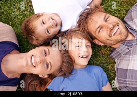 L'amore fa una famiglia. Ritratto di una famiglia amorevole giacente sull'erba insieme. Foto Stock