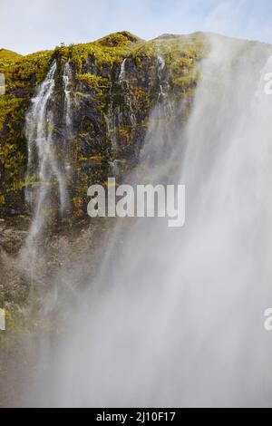 Irrorate in una giornata ventosa, alle Cascate Seljalandsfoss, vicino a Vik, Islanda meridionale. Foto Stock