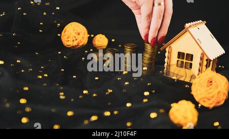 Donna che mette monete in pila per come risparmio per casa. Raccolto anonimo femmina raccolta monete in pila per gli investimenti immobiliari e risparmio di denaro per bu Foto Stock