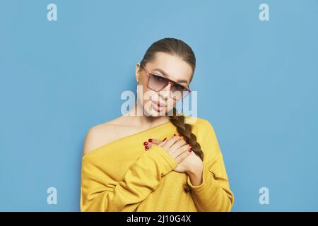 Primo piano su Wishful giovane donna pacifica che tiene le mani sul petto a cuore, facendo il desiderio, pregando, mostrando segno di gratitudine. Amore Ucraina concetto. Foto Stock