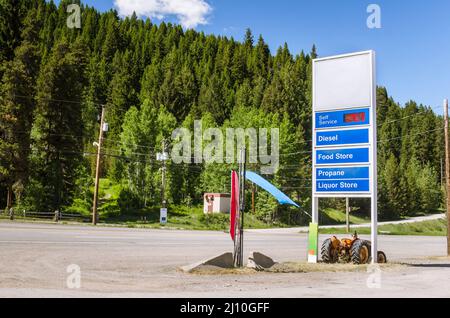Cartello per stazione di servizio lungo una strada di montagna. Aumento dei prezzi del gas. Foto Stock